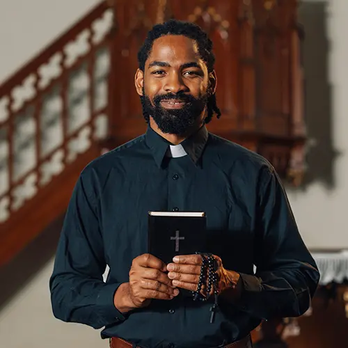a smiling priest holding the bible